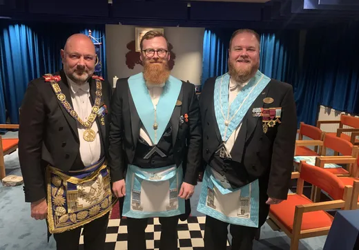 Tre brødre i kjole og hvidt står sammen på logens ternede gulv